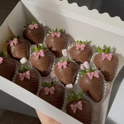 Milk chocolate strawberries each decorated with a pink bow.