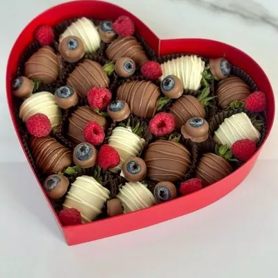 A heart-shaped box filled with chocolate-dipped strawberries, blueberries and raspberries.