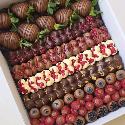 A grazing box filled with rows of chocolate-dipped berries in different finishes.