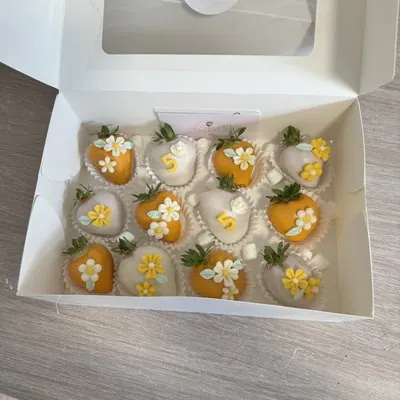 Strawberries in golden chocolate decorated with small yellow flowers.