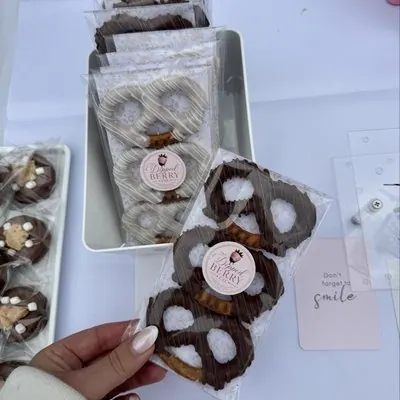 Chocolate-covered pretzels in clear bags with a branded sticker.