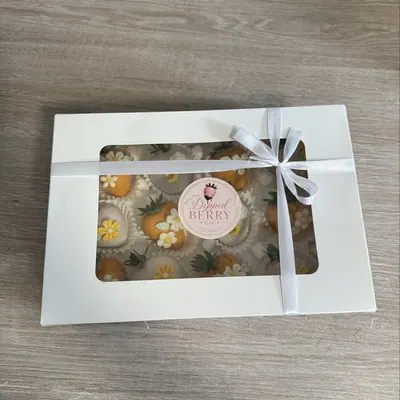 A window gift box tied with ribbon, holding golden floral strawberries.