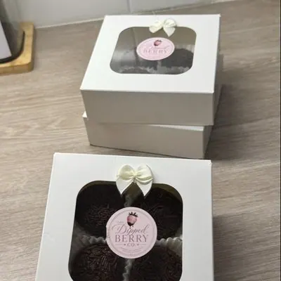 Two small white gift boxes with branded stickers, holding chocolate-dipped Oreos.