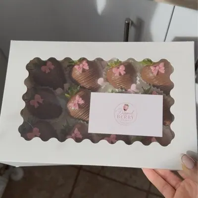 A gift box of chocolate strawberries with pink bows, with a branded label.