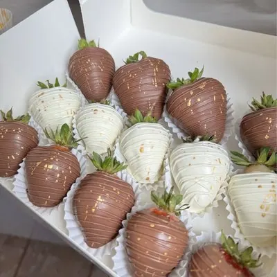 Milk and white chocolate strawberries with a gold drizzle, close up.