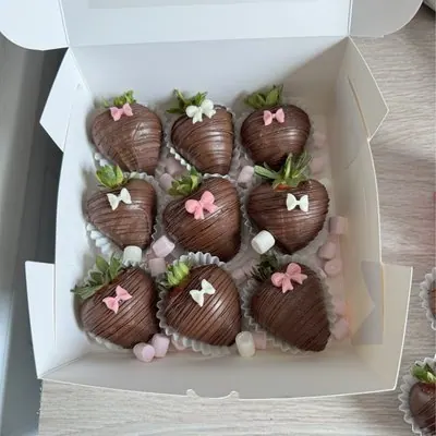 A box of nine chocolate strawberries with pink bows and marshmallows.