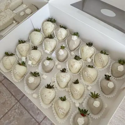 A box of cream and champagne chocolate strawberries decorated with pearl details.