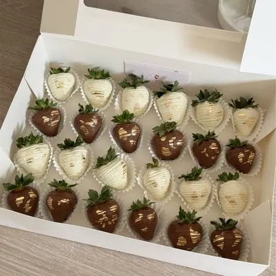 A large box of white and dark chocolate strawberries with gold detail.