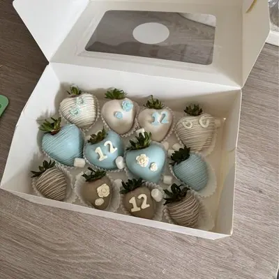 Blue and neutral chocolate strawberries decorated with the number 12 for a birthday.