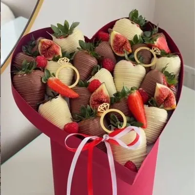 A heart-shaped bouquet of chocolate strawberries, figs and fresh fruit decorated with gold rings.