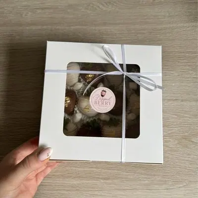 A ribbon-tied window gift box held in a hand.