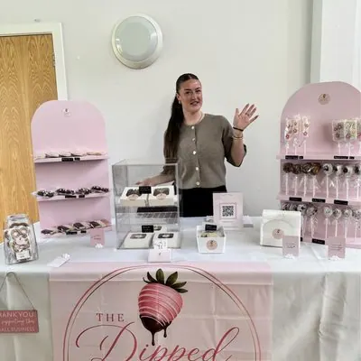 The Dipped Berry market stall, with the owner waving behind displays of treats.