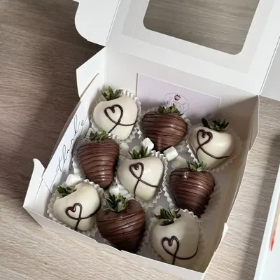 Milk and white chocolate strawberries decorated with piped hearts.