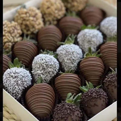 Chocolate strawberries topped with coconut, crushed nuts and drizzle.